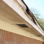 Overflowing old gutter system causing water damage to fascia