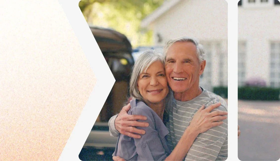 A older couple hugging and smiling in front of their newly renovated home exterior, part of The Eavestrough Company reviews and exterior renovation photo gallery