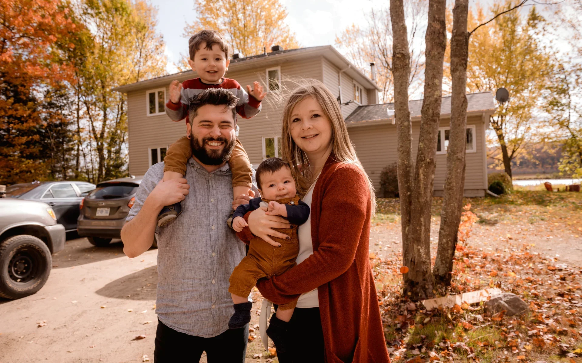 A family posing and smiling in front of their home after getting a free home exterior estimate from The Eavestrough Company