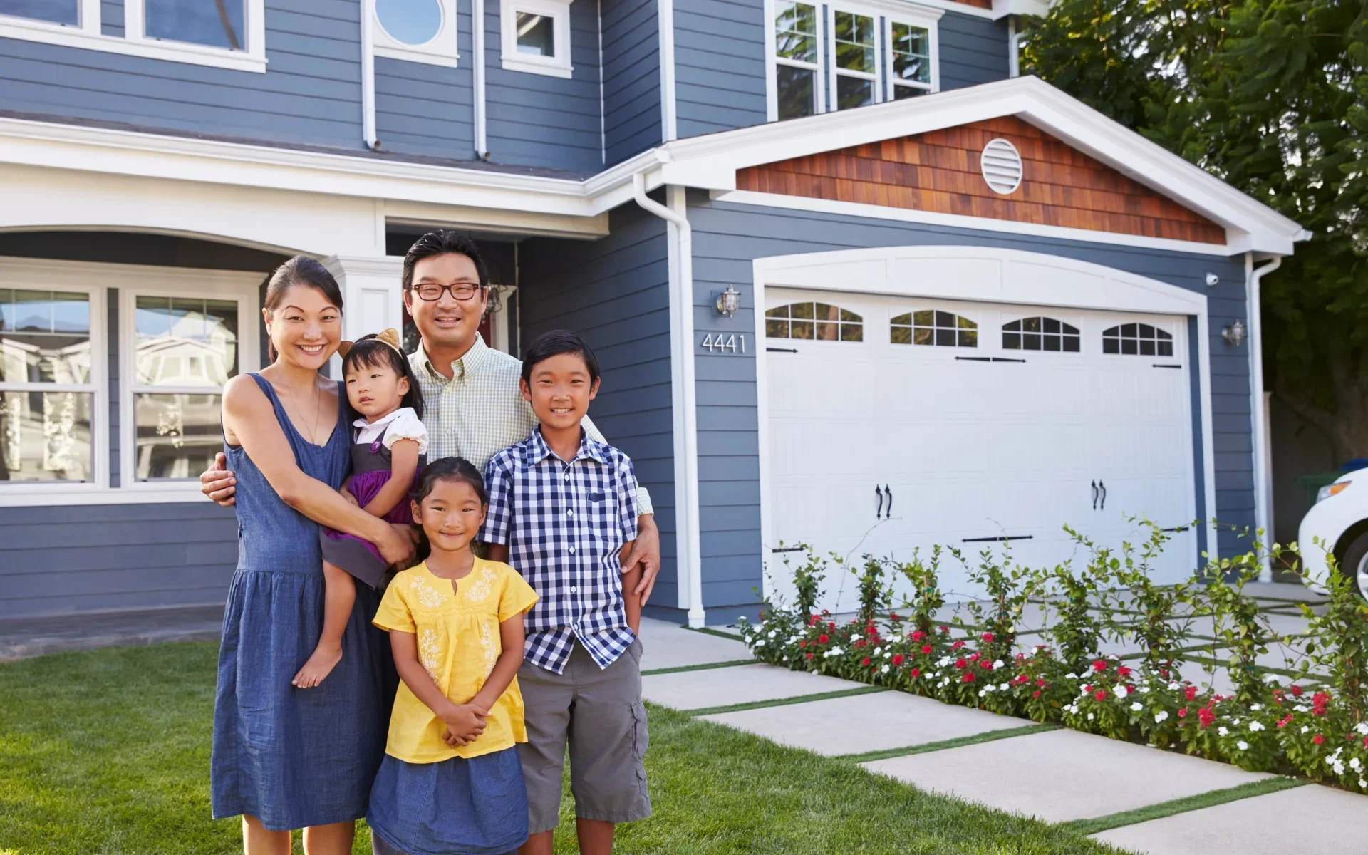 A family of 5 posing in front of their home after new eavestrough installation