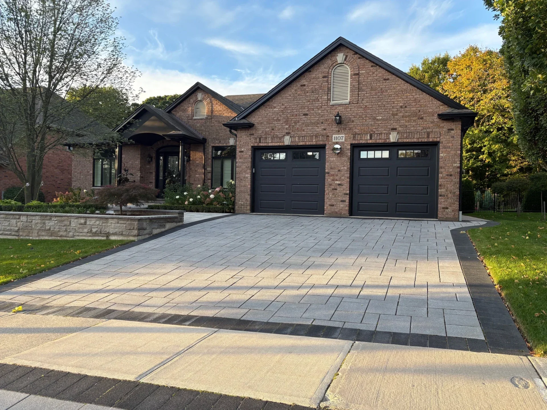 A view of the front of a brick home with newly installed black fascia and trim, part of The Eavestrough Company's exterior renovation photo gallery