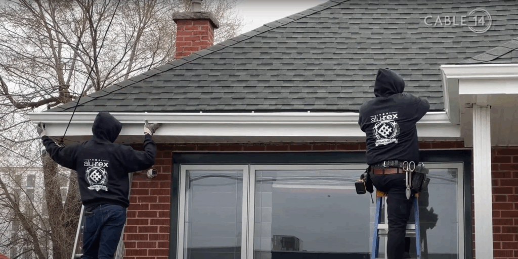 Two workers doing eavestrough installation on a house